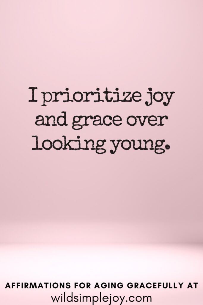 Vertical Pinterest Image on a pink background with text overlay i prioritize joy and grace over looking young Affirmations for Aging Gracefully at wildsimplejoy.com