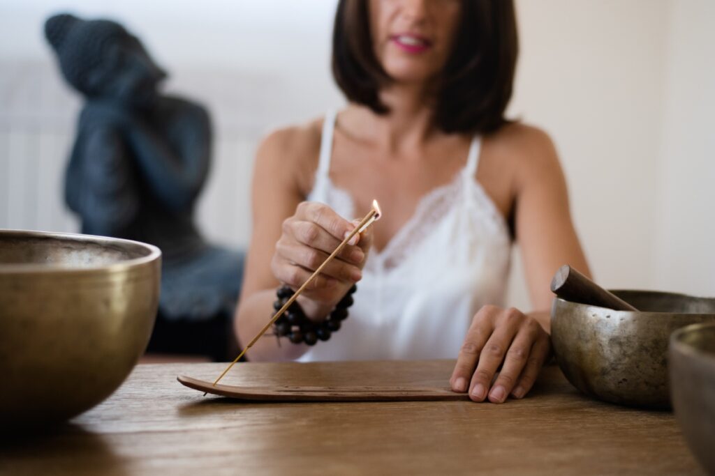 Woman lighting incense for a calm, peaceful, fulfilling new year in 2023