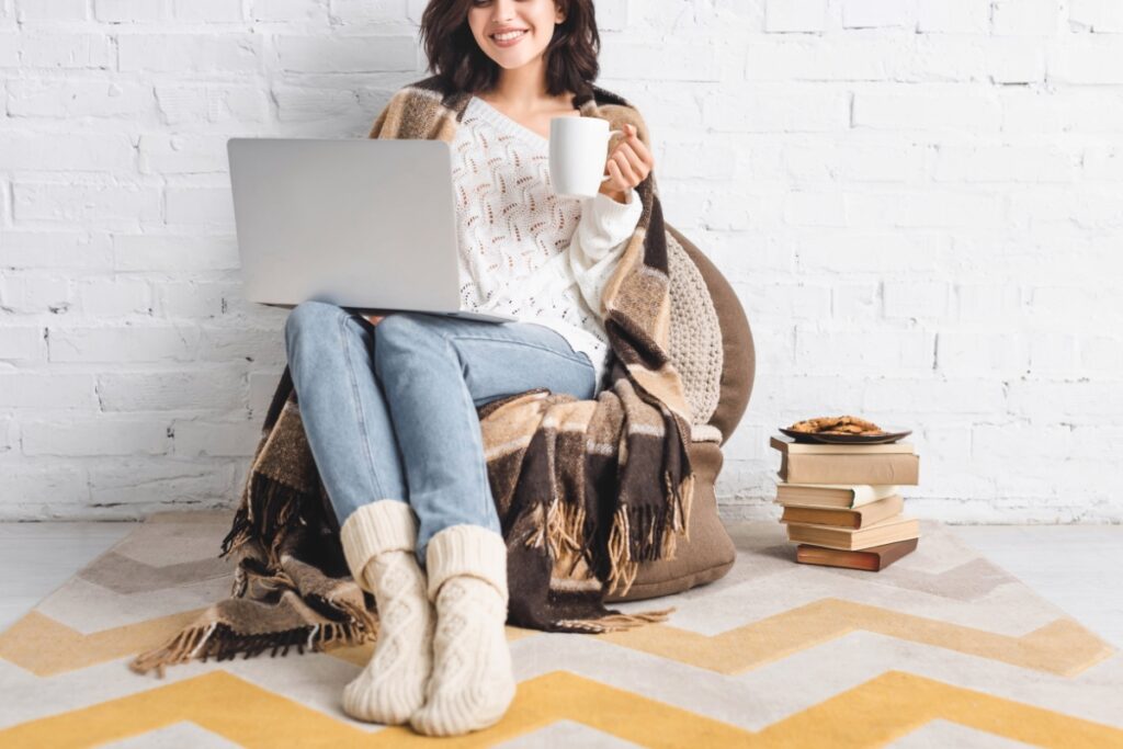 Woman on computer smiling with a cup of tea, ready for the new year
