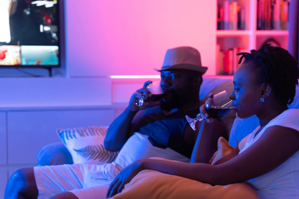 Married millennial couple sitting on the couch with glasses of wine