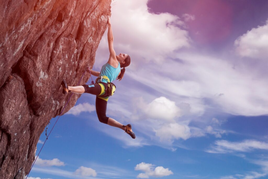 Woman rock climbing on a crag outdoors and achieving goals