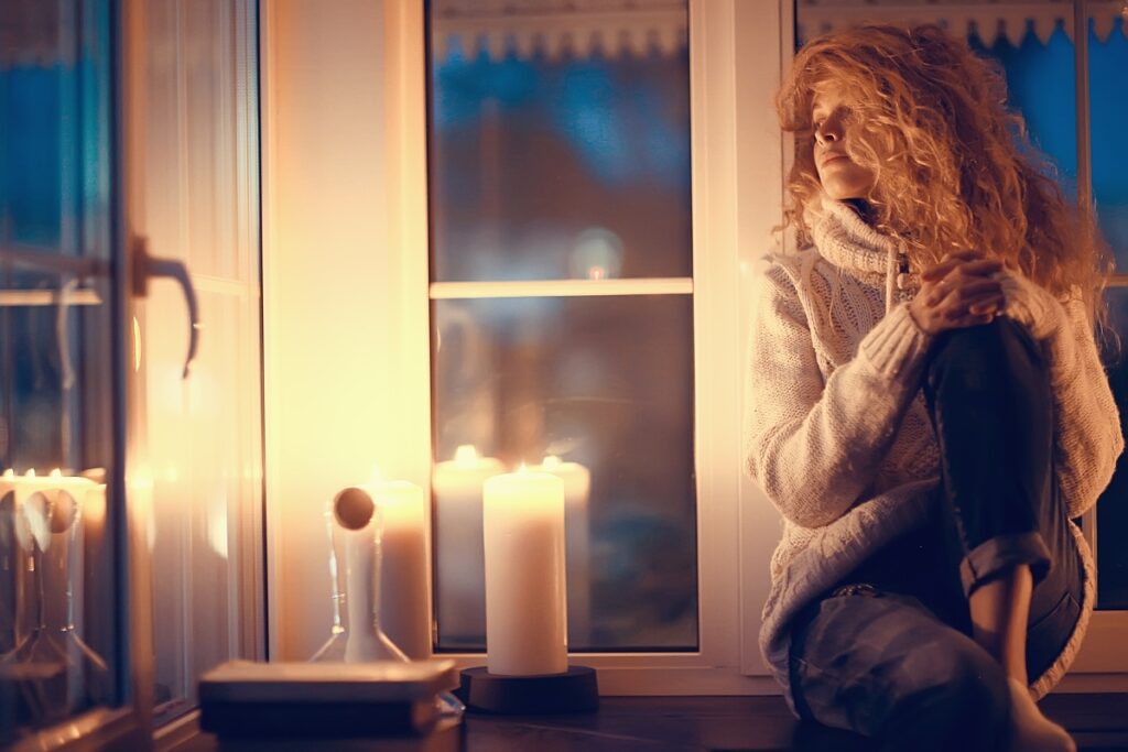 Woman sitting with candles on New Year's Eve, choosing a quiet, spiritual New Year