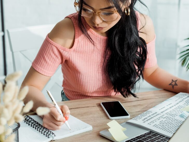 Woman writing in notebook a list of words