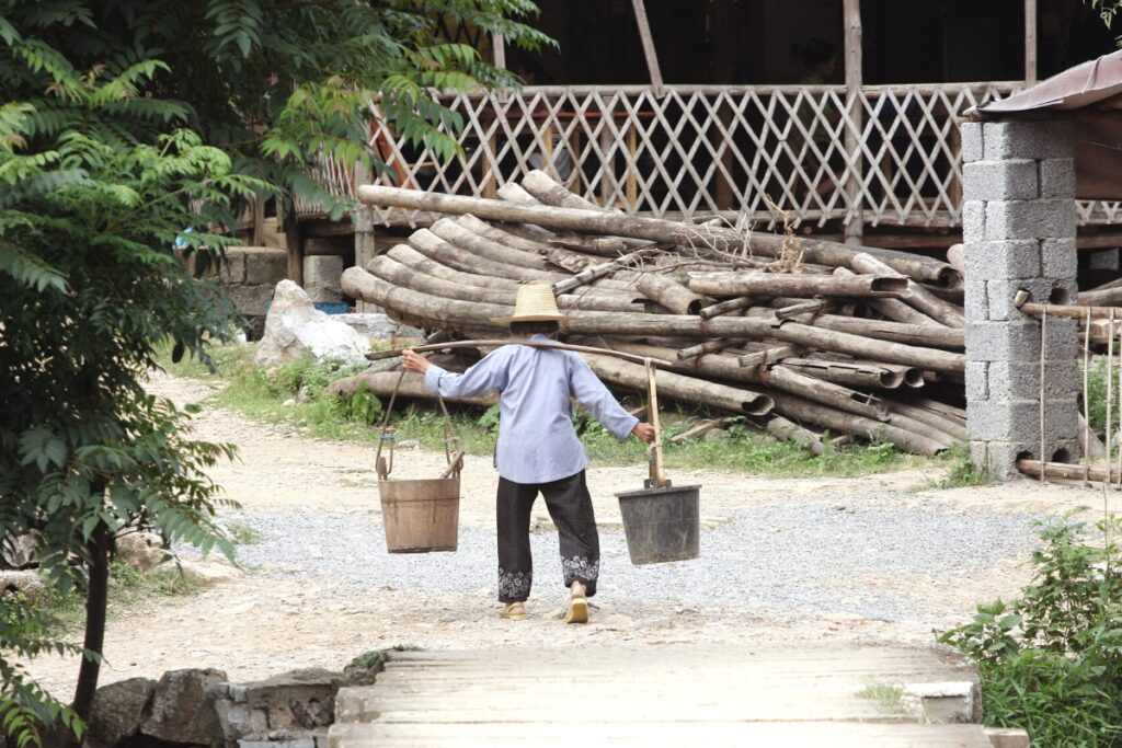 Old Chinese woman carrying water in pails
