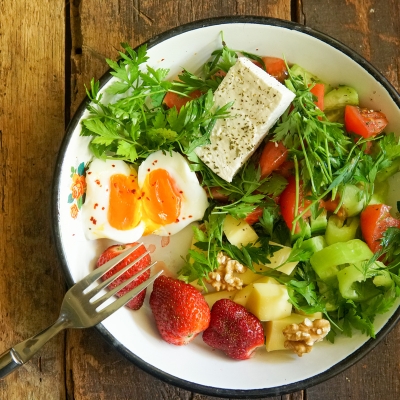 A healthy salad with veggies, fruit, and egg