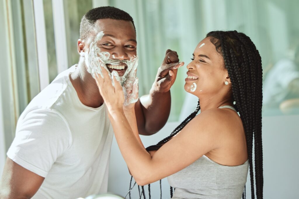 Couple looking in mirror, having fun smearing shaving cream
