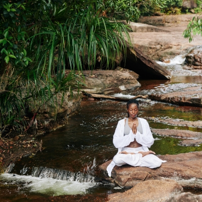 Woman meditating next to a river
