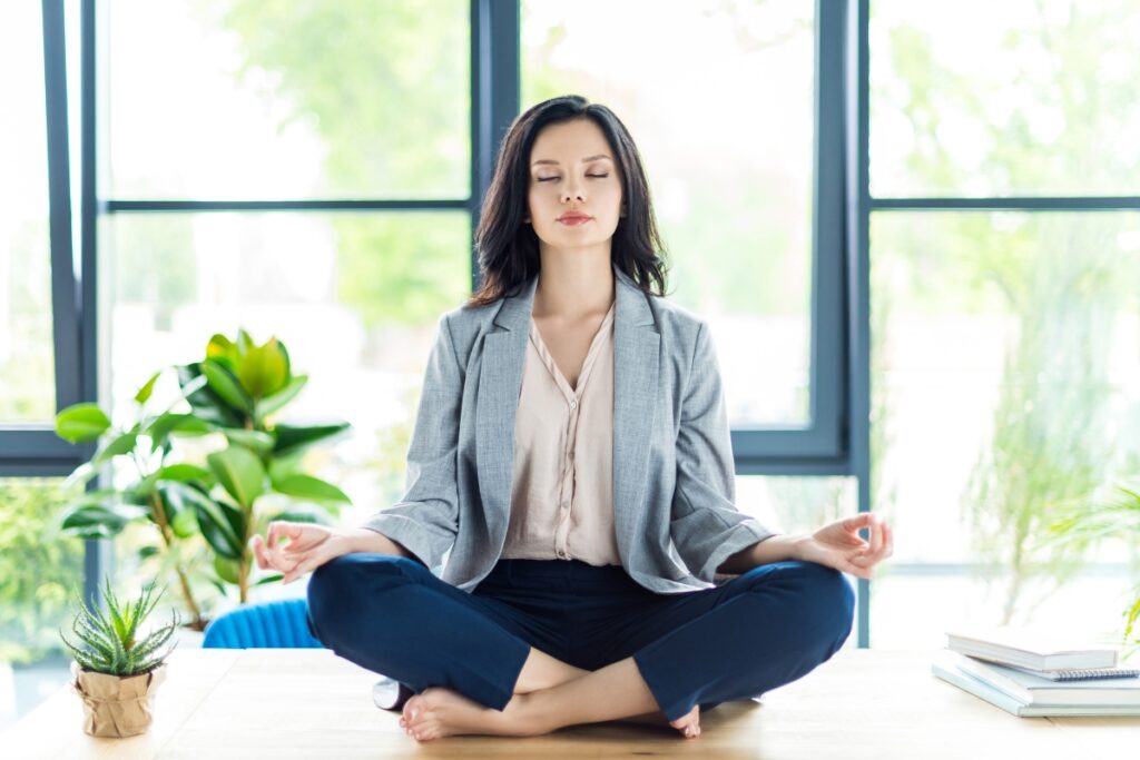Woman meditating on her desk at work