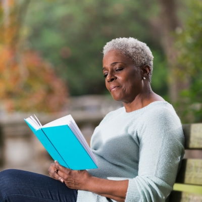 Woman in her 60s reading a book in the park