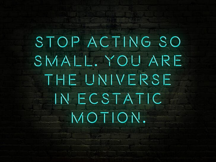 Horizontal image on black background with neon blue text, Stop acting so small. You are the Universe in ecstatic motion. Quote by Rumi Persian poet