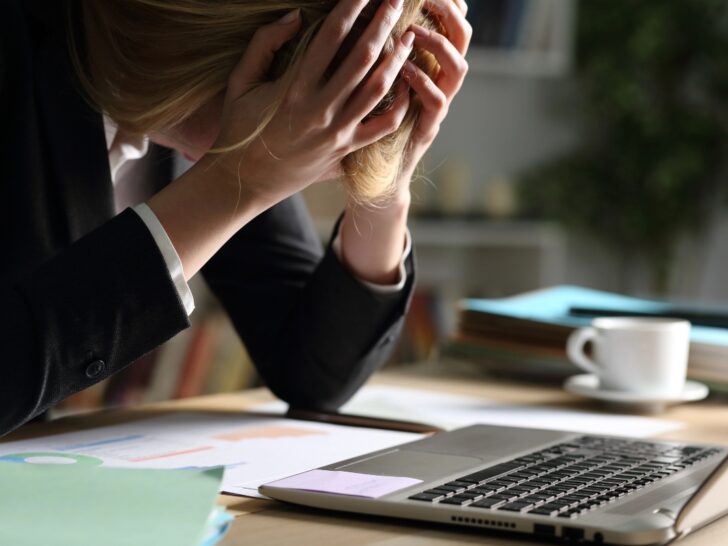 Woman wearing suit exhausted at work with her head in her hands