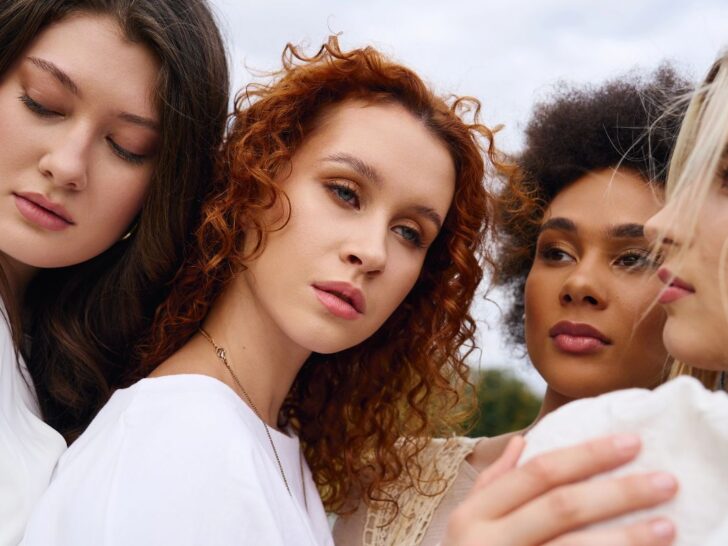Four women wearing white standing together with serious faces