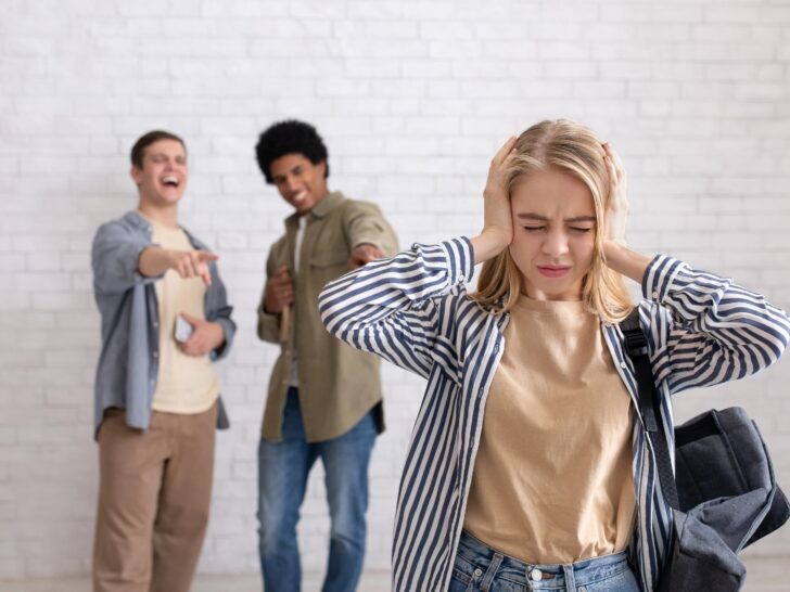Young woman trying not to hear others ridiculing her