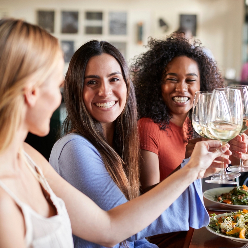 Women in restaurant celebrating with wine and toasting